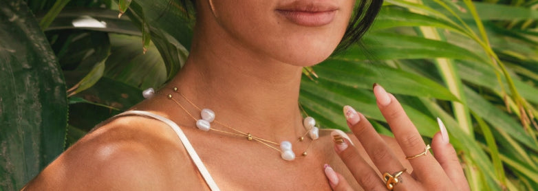 Colar de pérolas e anéis em cenário tropical